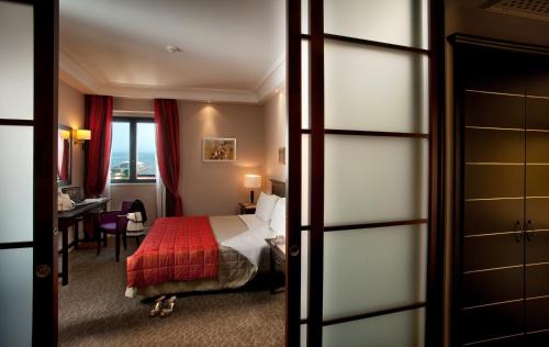 una camera d'albergo con un letto con una coperta rossa di Hotel Regina Margherita a Cagliari