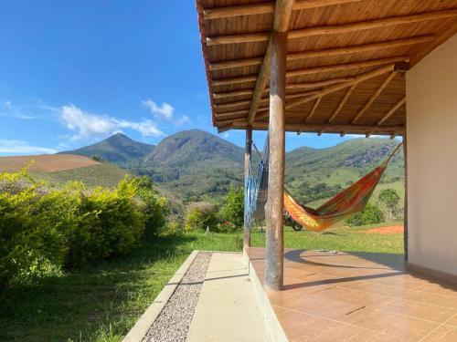 a hammock on a porch with mountains in the background at Hospedagem Colinas in Aiuruoca