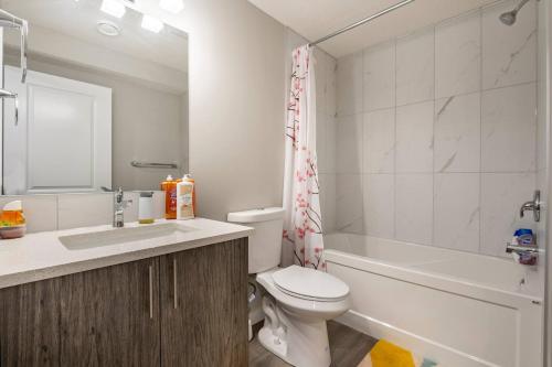 Un baño con inodoro, lavabo y bañera. en Luxurious Comfortable Suite, en Airdrie