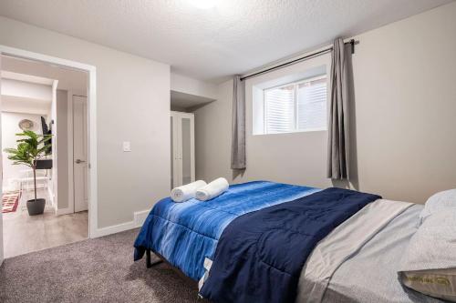 a bedroom with a bed with blue sheets and a window at Luxurious Comfortable Suite in Airdrie