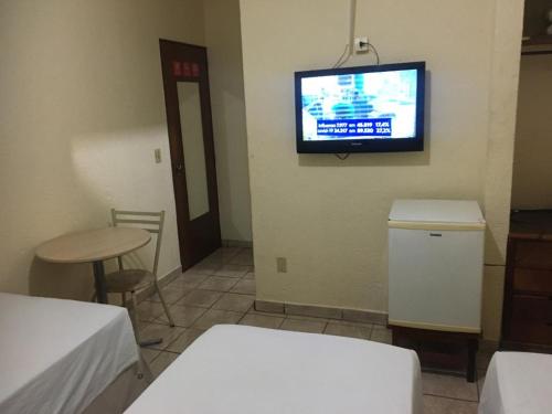 a room with a tv on the wall and a table at HOTEL CENTER Ribeirão in Ribeirão Preto