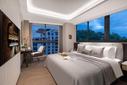 a bedroom with a large bed and a desk with a chair at Ascott Dadonghai Bay Sanya in Sanya