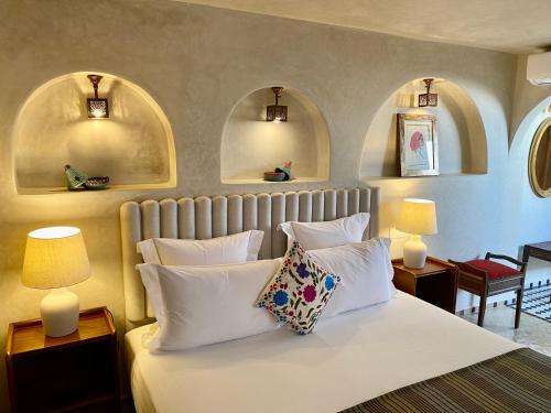 1 dormitorio con 1 cama con almohadas blancas y 2 lámparas en Riad Zamane & Spa Fès en Fez