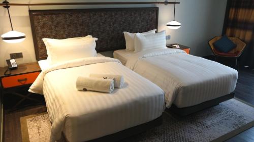 a hotel room with two beds with towels on them at The George Penang by The Crest Collection in George Town