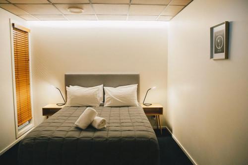 a bedroom with a bed with two pillows and two lamps at Liberty Apartment Hotel in Wellington