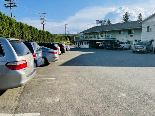 a parking lot with cars parked in front of a building at Fraser Bridge Inn in Quesnel