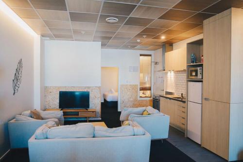 een woonkamer met 2 banken en een televisie bij Liberty Apartment Hotel in Wellington
