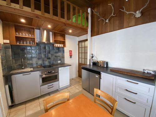 a kitchen with white cabinets and a table with chairs at Mount Buller Apartment in Mount Buller