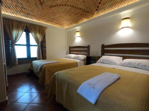 a hotel room with two beds and a window at Hotel Santa Irene in Cholula