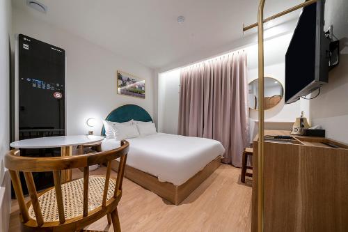 a hotel room with a bed and a table and a tv at Wonju Hotel Ippda in Wonju