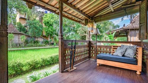 a porch with a blue couch on a wooden deck at KajaNe Yangloni at Ubud Bali in Ubud