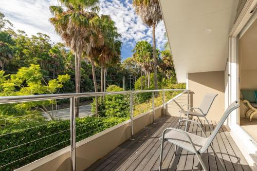 a balcony with two chairs and palm trees at The Beach House at Lizzie in Elizabeth Beach