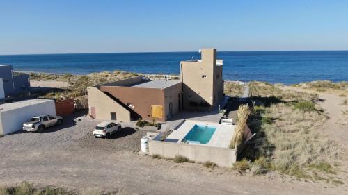 une maison avec une voiture garée à côté de l'océan dans l'établissement Las Piedritas Casa de Mar Loft, à Las Grutas