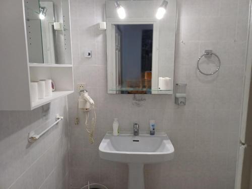 Baño blanco con lavabo y espejo en Estudio Grande Madrid Centro, en Madrid