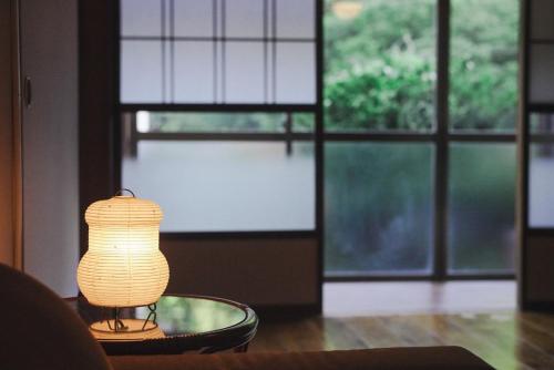 a lamp sitting on a table in a room with a window at Kominkayado LOOF Sakanoie in Fuefuki