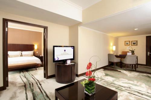 um quarto de hotel com uma cama e uma televisão em Grand Mercure Beijing Central em Pequim