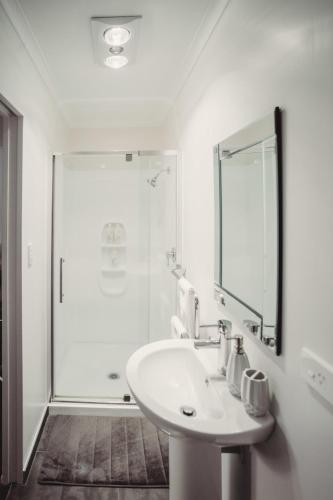 a white bathroom with a sink and a shower at Paradise Valley Lodge in Rotorua