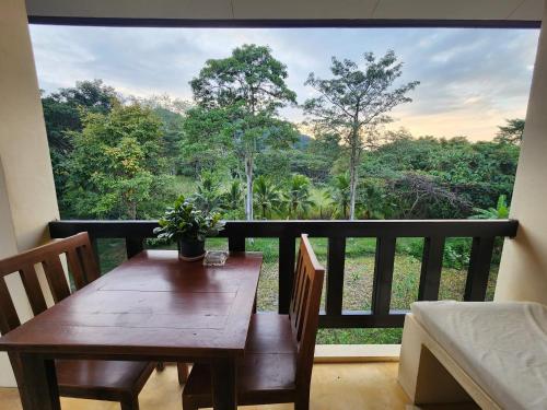 a wooden table and chairs on a balcony with a view at Villa Khao Phaengma in Wang Nam Khieo