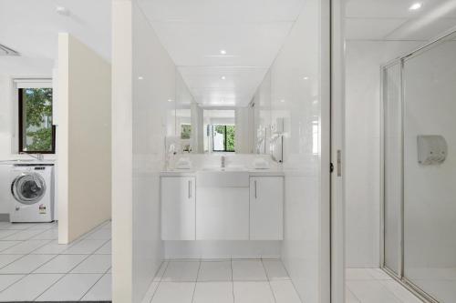 a white bathroom with a sink and a washing machine at Manuka Park Serviced Apartments in Canberra