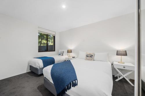 2 camas en una habitación blanca con ventana en Manuka Park Serviced Apartments, en Canberra