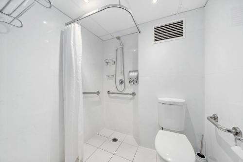 a white bathroom with a shower and a toilet at Manuka Park Serviced Apartments in Canberra