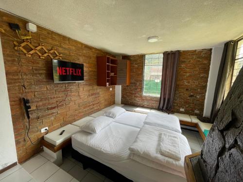 a bedroom with a bed and a brick wall at Mountain Chalet - Tungurahua Hot Springs/Aguas Termales in Baños