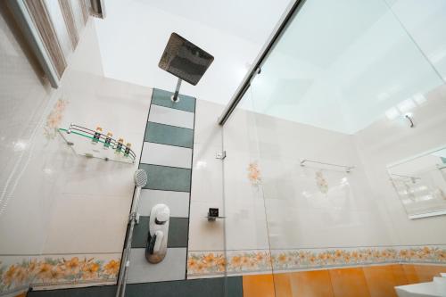 La salle de bains est pourvue d'une douche et d'une paroi en verre. dans l'établissement Parudeesa - Kerala, à Kāladi