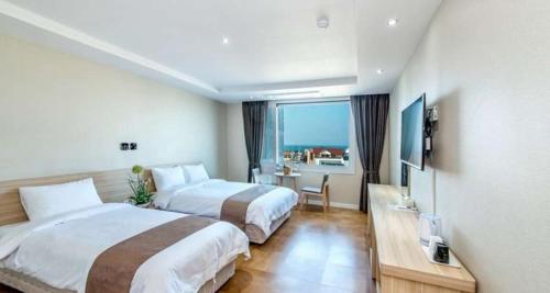 um quarto de hotel com duas camas e uma grande janela em Jeju In Hotel em Jeju