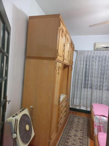 a room with a large wooden cabinet and a fan at cousy apartment in Cairo