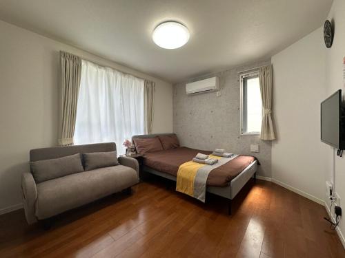 a bedroom with a bed and a couch and a chair at nestay inn tokyo ryogoku in Tokyo