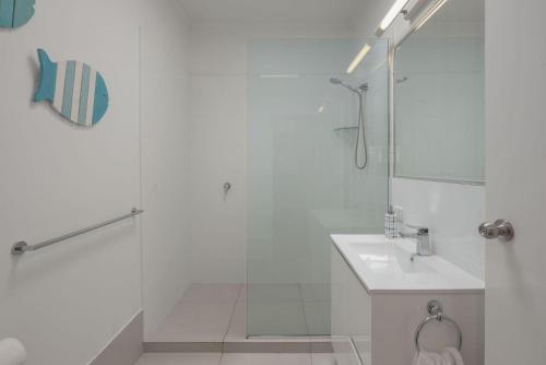 een witte badkamer met een douche en een wastafel bij 15 Seaview Terrace Moffat Beach QLD in Caloundra