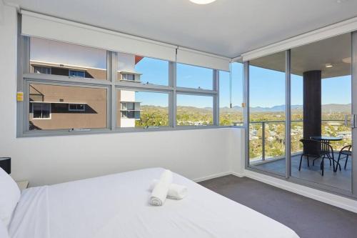 a bedroom with a white bed and a large window at Two bedroom Apartment in Robina Center in Gold Coast