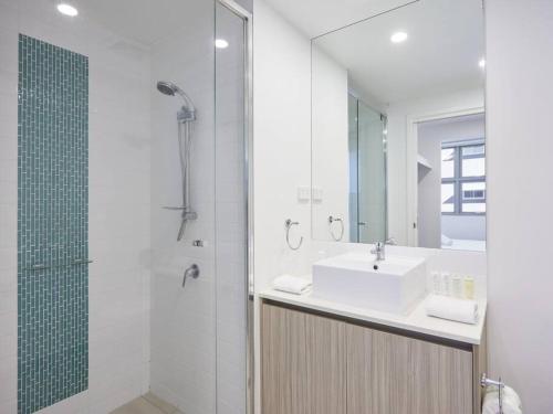 a white bathroom with a sink and a shower at Two bedroom Apartment in Robina Center in Gold Coast