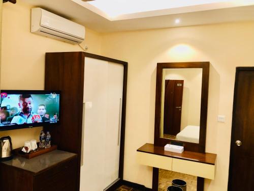a hotel room with a television and a mirror at Tropic Inn - Mount Lavinia in Mount Lavinia