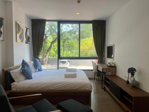 um quarto com uma cama, uma secretária e uma janela em Deluna 23degree by The valley khao yai em Pak Chong