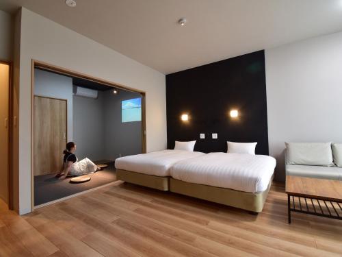a woman sitting on the floor of a hotel room at Rakuten STAY MOTEL Kujukurihama Katakai 202 1LDK with BBQ terrace in Kujukuri