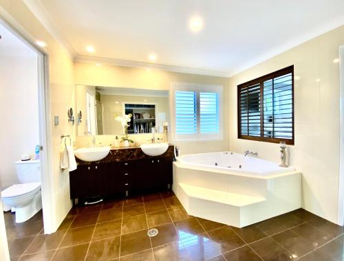 un bagno con due lavandini, una vasca e un WC di Casuarina Beach 4 bedroom home a Casuarina