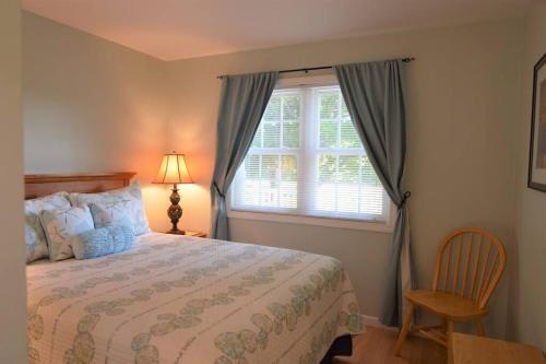 1 dormitorio con cama, ventana y silla en Carraig Dale Cottage, en Fish Creek