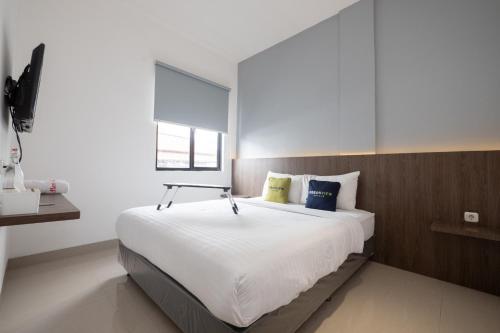 a bedroom with a large white bed with a window at Urbanview Hotel Max Living Cengkareng in Jakarta