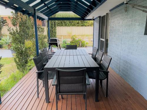 una mesa de madera y sillas en una terraza en Blue Tides Accommodation, en Esperance