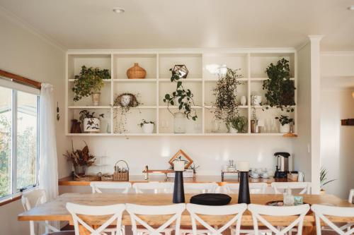 ein Esszimmer mit einem Tisch und Stühlen sowie Regalen mit Pflanzen in der Unterkunft Paradise Valley Lodge in Rotorua