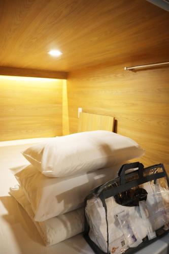 a bedroom with a bed with white pillows and a bag at AMANGO HOSTEL in Ho Chi Minh City
