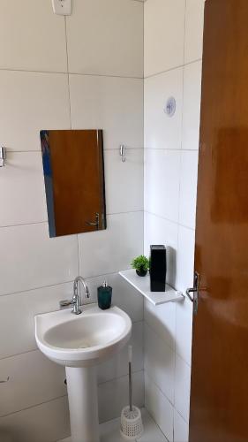 uma casa de banho branca com um lavatório e um espelho em Tangará da Serra em Tangara da Serra