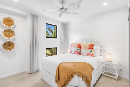 een witte slaapkamer met een wit bed en een oranje deken bij Belle Escapes Havenly Luxury Villa Palm Cove in Palm Cove