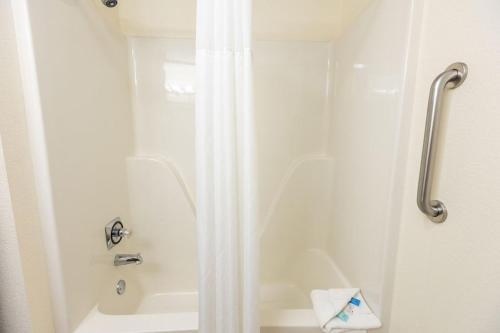 a shower with a white shower curtain in a bathroom at Savannah House Hotel in Branson