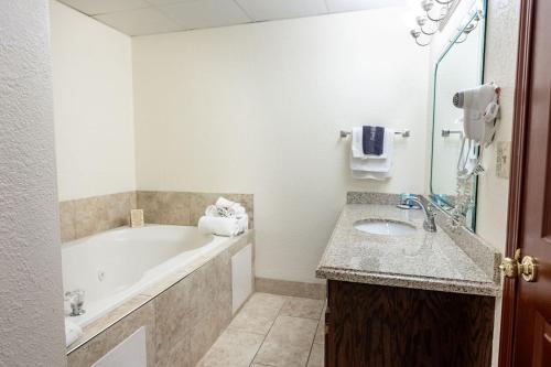a white bathroom with a tub and a sink at Savannah House Hotel in Branson