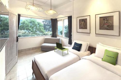 a small bedroom with two beds and a chair at Urbanview Wisma Nirwana Tretes by RedDoorz in Pasuruan