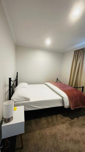 a bedroom with a bed and a table with a night stand at Stay with the Singhs in Rolleston
