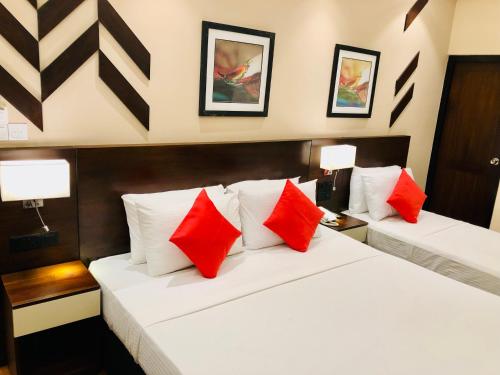 two beds in a hotel room with red pillows at Tropic Inn - Mount Lavinia in Mount Lavinia