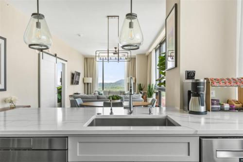 a kitchen with a sink and a living room at 'Cloud 10' A Luxury Downtown Condo with Panoramic City and Mountain Views at Arras Vacation Rentals in Asheville